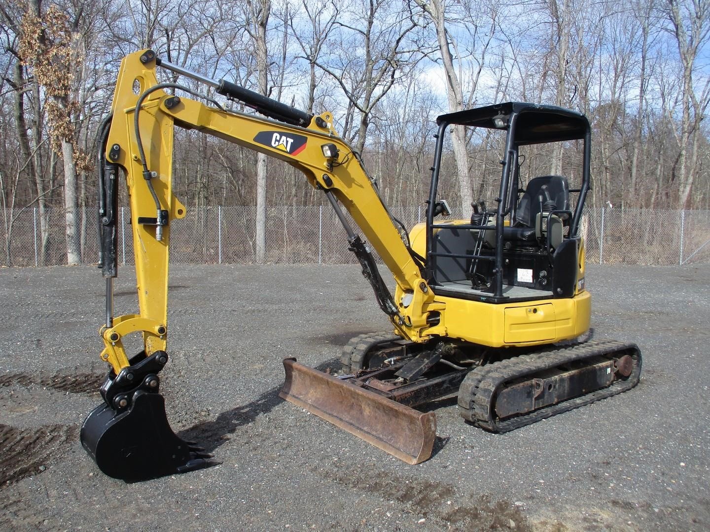 Compact excavator staged for utility and drainage work